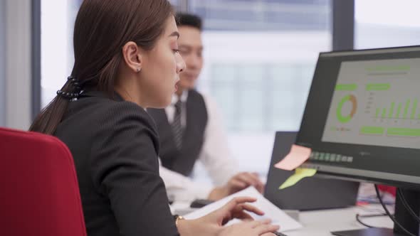 Asian young business man and woman typing on computer keyboard, working and plan as team in office. alt