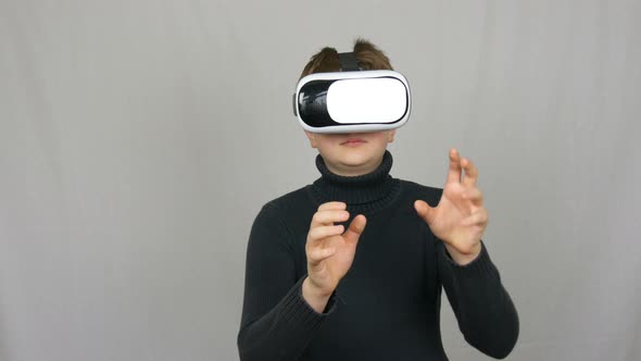 Teenager Boy Looks Into White Virtual Reality Glasses or VR and Has Fun on a White Background in the alt