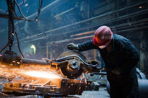 Male worker wearing special protective gloves, cutting metal with big electric grinder, orange - Stock Photo - Images