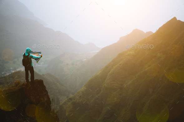 Man with the map staying on top of the mountain rock with gorgeous panorama view over high mountain - Stock Photo - Images