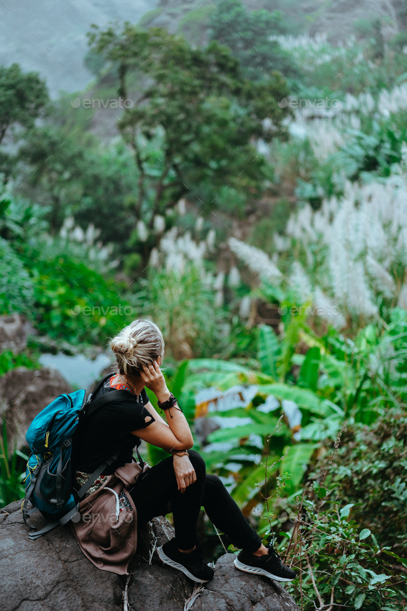 Girl resting after track on the stone and admiring spectacular green banana and sugarcane plants on - Stock Photo - Images