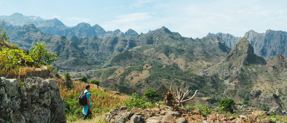Man hiker walking among remote mountainous landscape with agriculture terraces in vertical valley - Stock Photo - Images