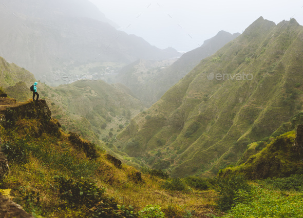 Hiker with backpack on the top of mountain edge. Rocky terrain in front of a incredible panorama - Stock Photo - Images