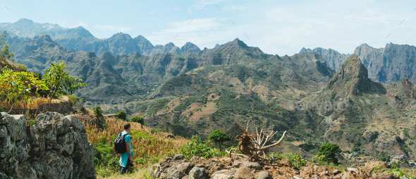 Man hiker walking among remote mountainous landscape with agriculture terraces in vertical valley - Stock Photo - Images
