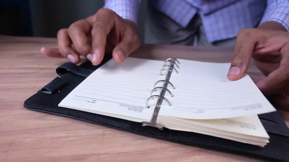 Close Up of Man's Hand Turning a Pager of a Diary  alt