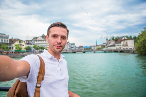 Young man taking selfie background famous Fraumunster Church and river  Limmat, Switzerland Stock Photo by travnikovstudio