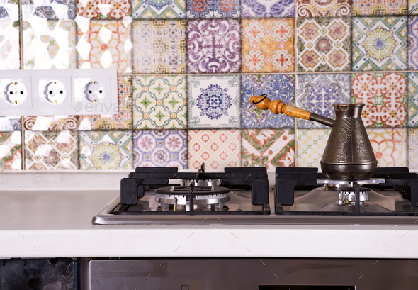 Cooking coffee on a gas stove. Old turkish copper pot for brewing coffee on stove in the kitchen - Stock Photo - Images