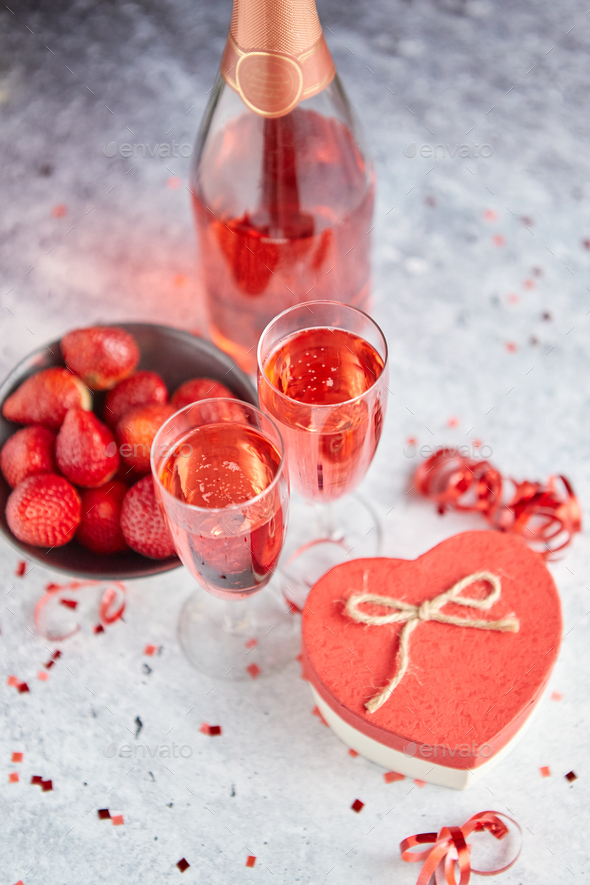 Bottle of rose champagne, glasses with fresh strawberries and heart shaped gift - Stock Photo - Images