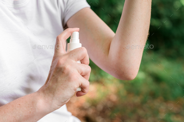 Female hiker using antiseptic spray outdoors - Stock Photo - Images