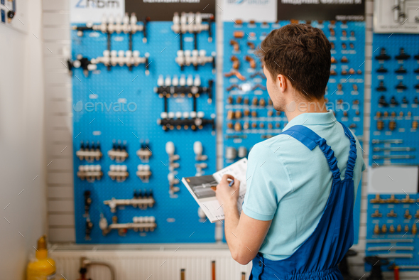 Plumber at showcase with valves and pipe equipment - Stock Photo - Images