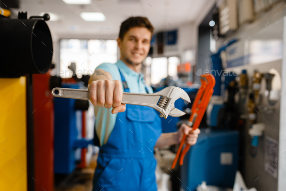 Plumber shows pipe wrenches in plumbering store - Stock Photo - Images