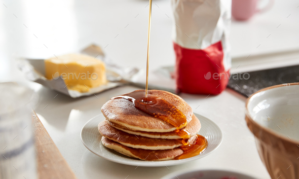 Maple Syrup Being Poured On Stack Of Freshly Made Pancakes Or Crepes On Table For Pancake Day