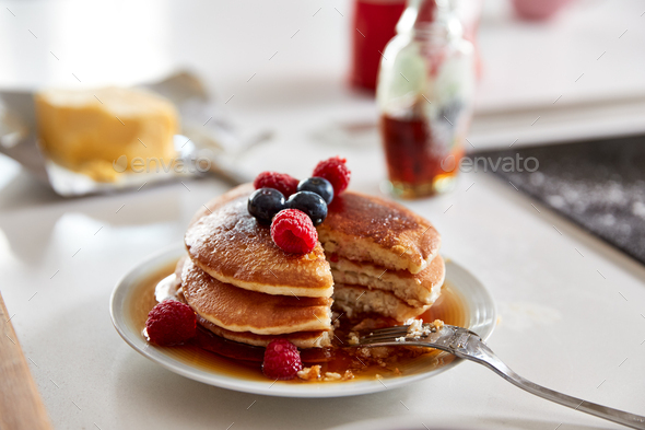 Stack Of Freshly Made Pancakes Or Crepes With Maple Syrup And Berries On Table For Pancake Day