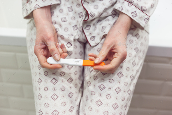Rapid pregnancy test with negative result in woman's hand sitting in bathroom. - Stock Photo - Images