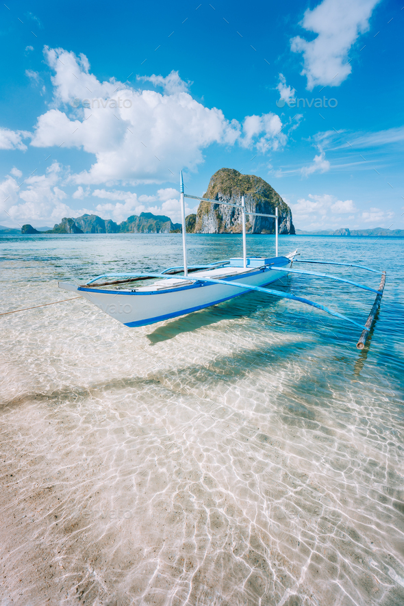 El Nido, Palawan, Philippines. Banca boat on sandy beach in shallow crystal clear water on island - Stock Photo - Images