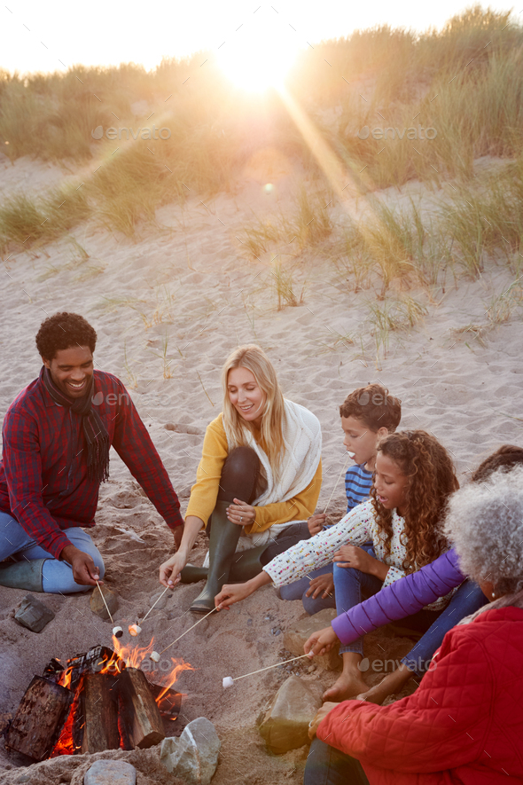 Multi-Generation Family Toasting Marshmallows Around Fire On Winter Beach Vacation