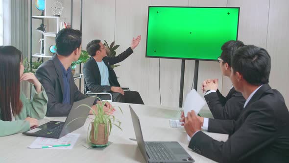 Young Asian Businessman Presentation To His Business Colleagues, Pointing At Tv Mock Up Green Screen alt