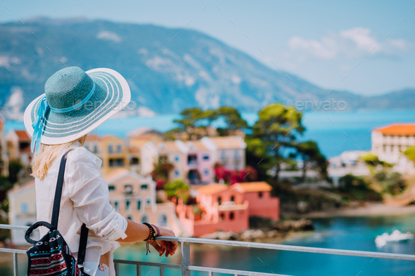 Tourist woman wearing blue sunhat and white clothes enjoying view of colorful tranquil village Assos - Stock Photo - Images