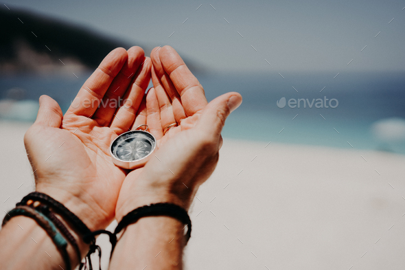 Man's hand holding compass against the backdrop of beach and sea. The concept of travel, summer - Stock Photo - Images
