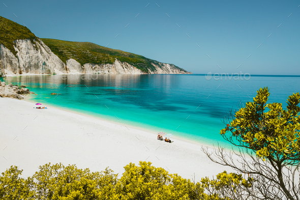 Amazing Fteri beach lagoon, Cephalonia Kefalonia, Greece. Tourists under umbrella relax near clear - Stock Photo - Images
