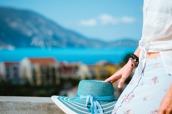 Blue sunhat laying on the wall. Tourist woman enjoying view of colorful tranquil village Assos on - Stock Photo - Images