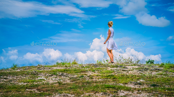 A girl standing on Hill and looking at the white clouds, Teletubbies Hills, Nusa Penida, Bali - Stock Photo - Images