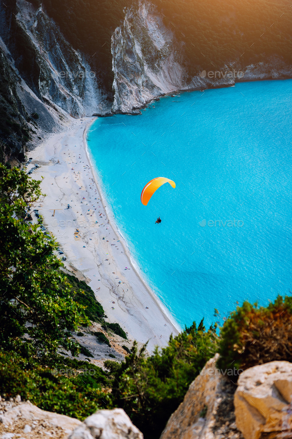 Myrtos Beach, Kefalonia Island, Greece. Figure of a parachutist skydiver with orange parachute - Stock Photo - Images