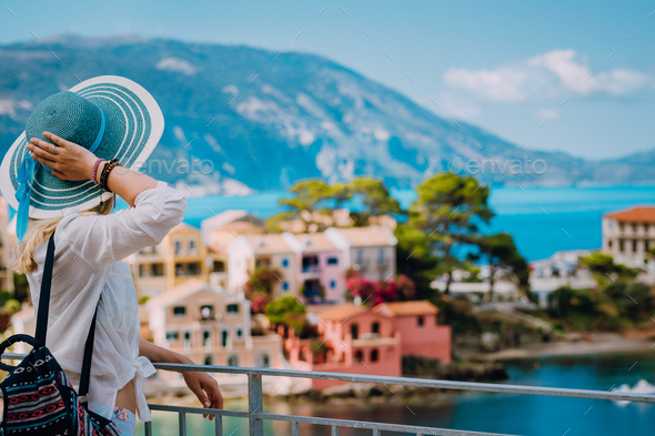 Tourist woman wearing blue sunhat and white clothes enjoying view of colorful tranquil village Assos - Stock Photo - Images
