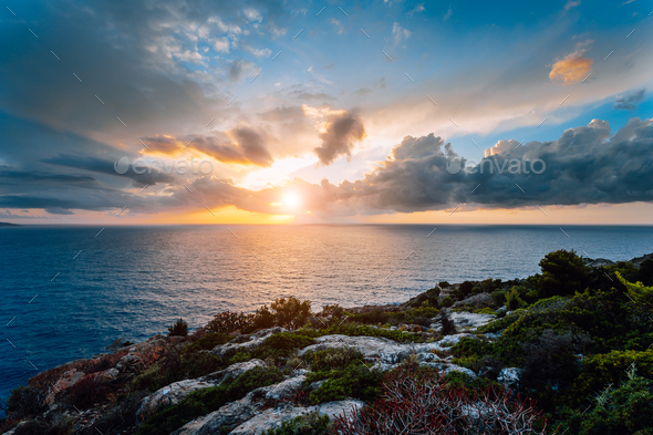 Dramatic moody sunset on the coastline near Assos place on Kefalonia Island. Motion clouds on - Stock Photo - Images
