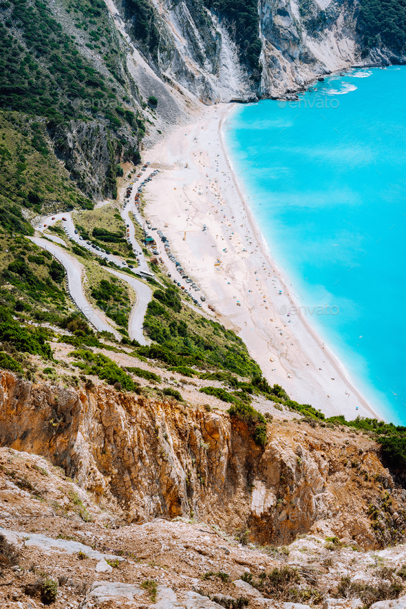 Serpentine zigzag road down to famous Myrtos Beach. Many tourists on the sunny beach, Kefalonia - Stock Photo - Images