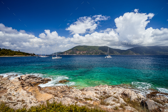 Crystal clear transparent blue turquoise teal Mediterranean sea water in Fiskardo town. White yacht - Stock Photo - Images