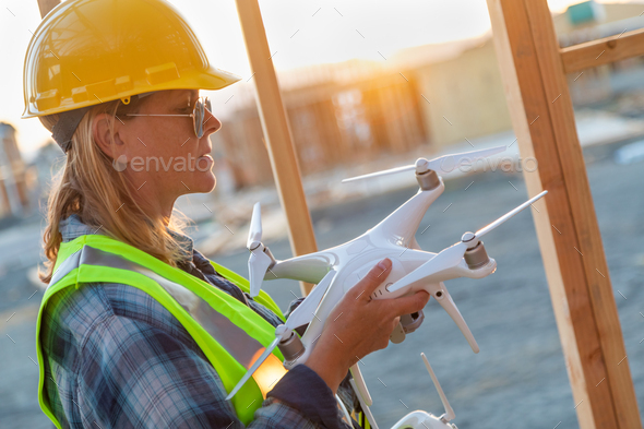 Female Unmanned Aircraft System (UAS) Quadcopter Drone Pilot Holding Drone at Construction Site - Stock Photo - Images