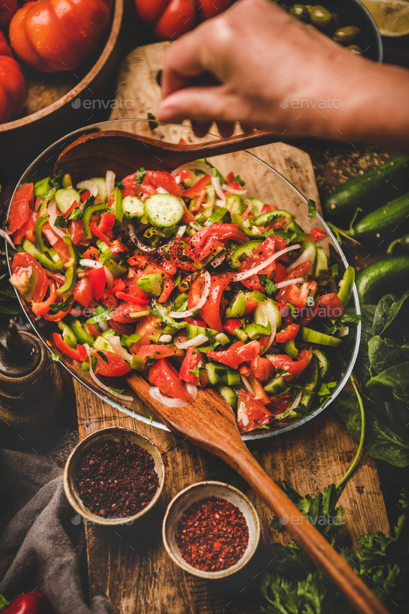 Womans hands adding spices to Turkish Chopard Salad with vegetables - Stock Photo - Images