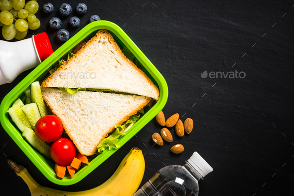 Lunch box with sandwich and fruits on black - Stock Photo - Images