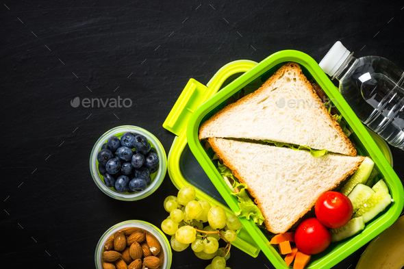Lunch box with sandwich and fruits on black - Stock Photo - Images