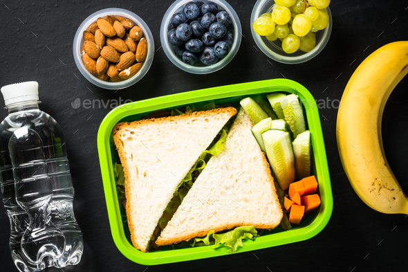 Lunch box with sandwich and fruits on black - Stock Photo - Images