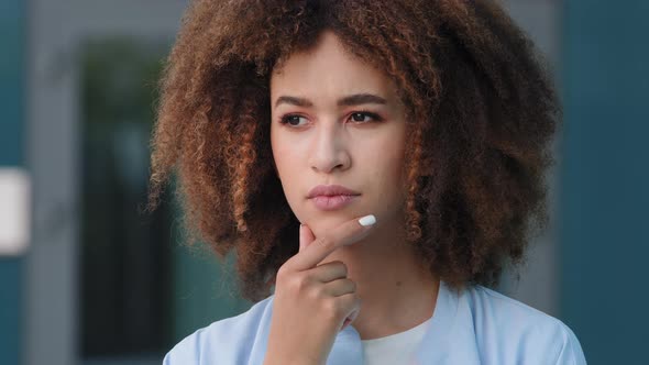 Millennial Black African American Young Pensive Girl Woman with Curly Hair Deep in Thoughts Thinking alt