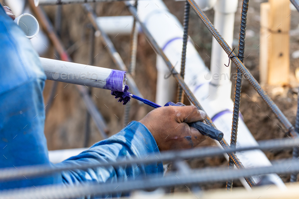 Plumber Applying Pipe Cleaner, Primer and Glue to PVC Pipe At Construction Site