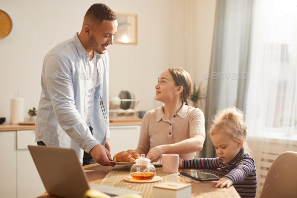 Modern Family Using Gadgets at Breakfast in Cozy Kitchen Stock