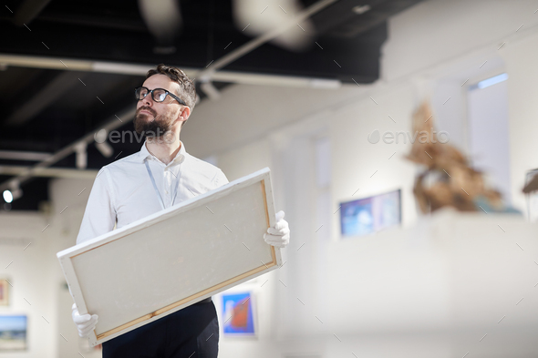 Bearded Worker Holding Painting in Art Gallery