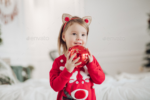 Lovely little girl in red dress with Christmas present - Stock Photo - Images