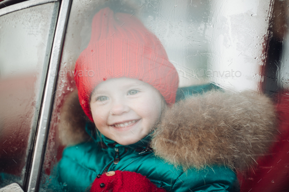 Smiling cute winter girl in red hat sitting in car having fun - Stock Photo - Images