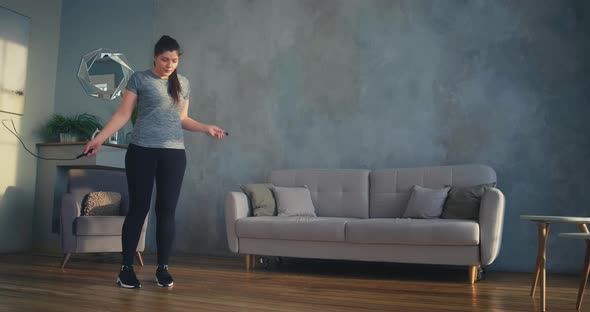 Woman in Sportswear and Shoes Jumps Rope on Laminate in Room