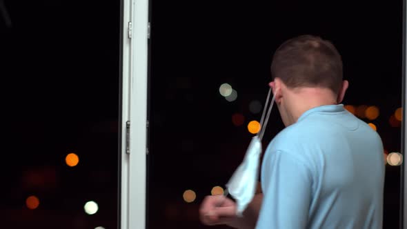 The man removes the medical mask going to the open window alt