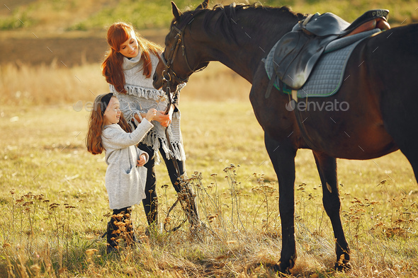 Mother and daughter in a field playing with a horse - Stock Photo - Images