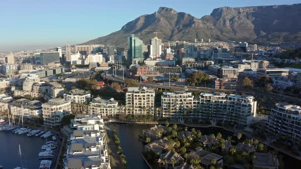 Tracking aerial shot of the city, mountain and marina in Cape Town.