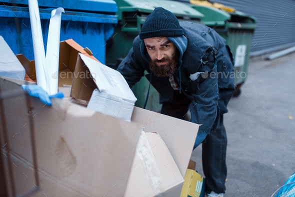 Bearded homeless searching food in trashcan - Stock Photo - Images