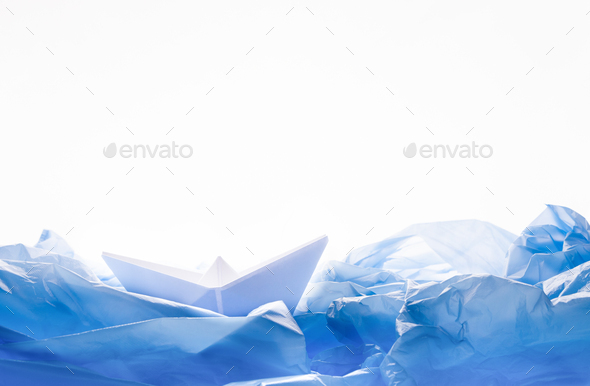 Paper boat in water of plastic bags over white background
