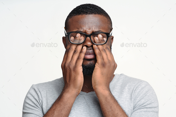 Afro guy in glasses rubbing his eyes