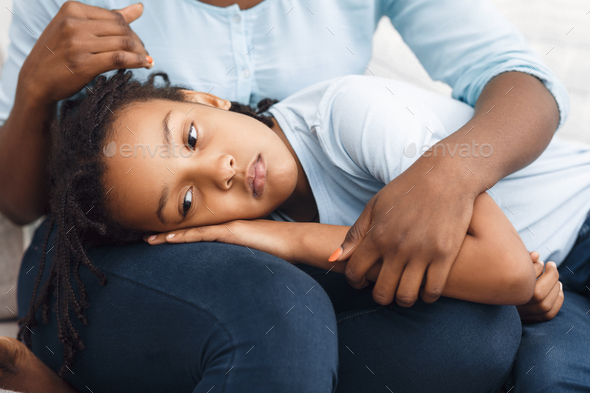 Black daughter lying her head on mom\'s lap